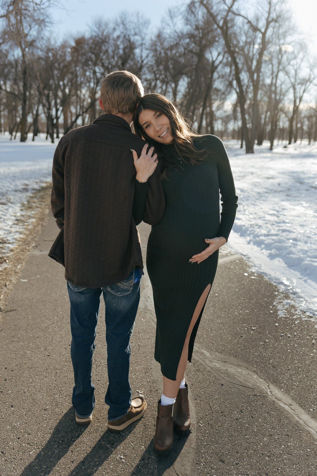 Mother to be holding arm of father to be in winter season for maternity session in Bismarck