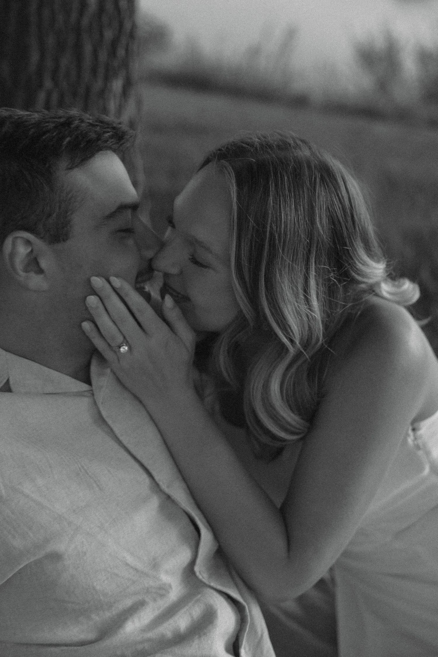 A romantic black and white photo sequence of a couple sharing tender kisses by a lake.