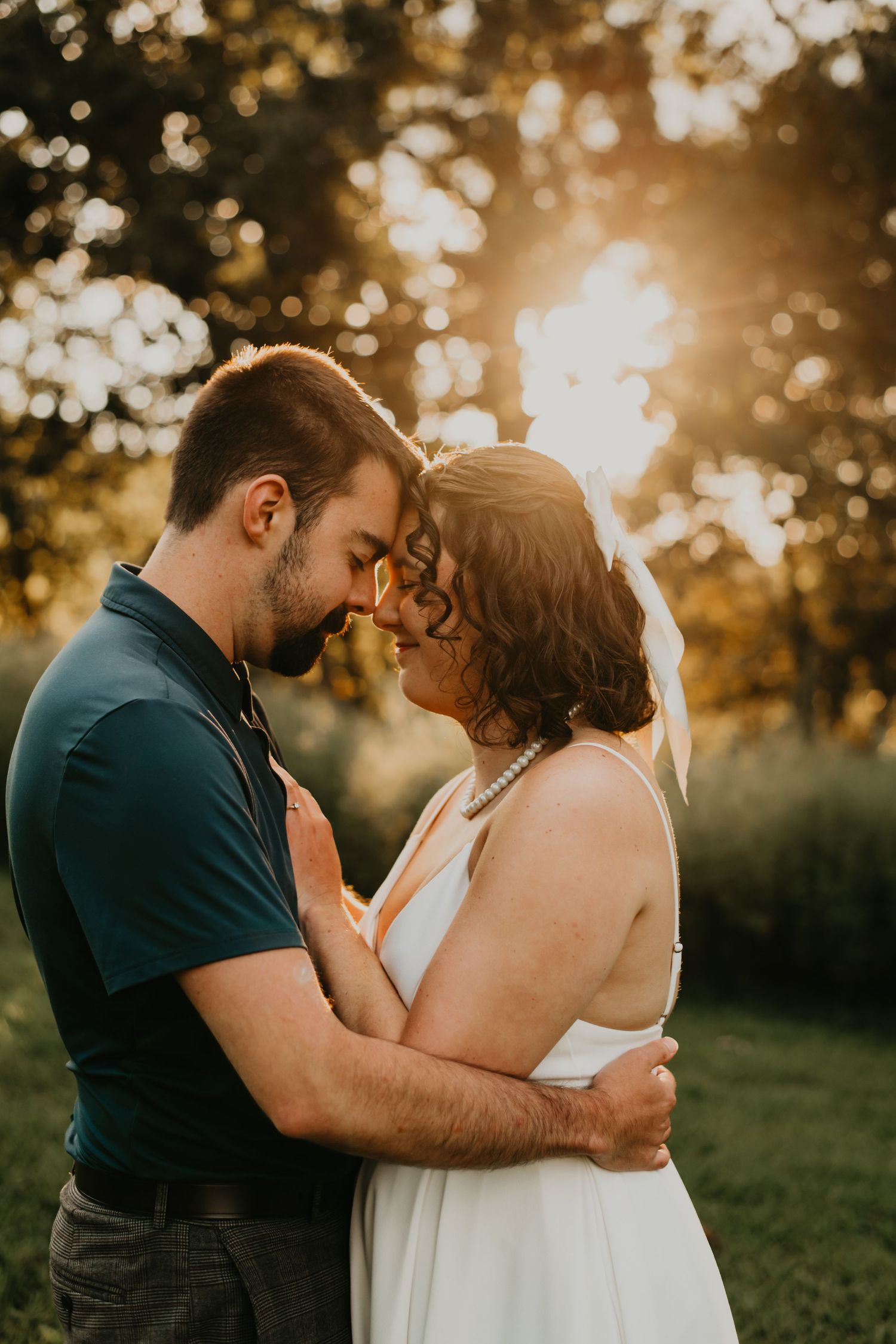 Newlywed couple embraces during golden hour sunset in a romantic outdoor photo shoot.