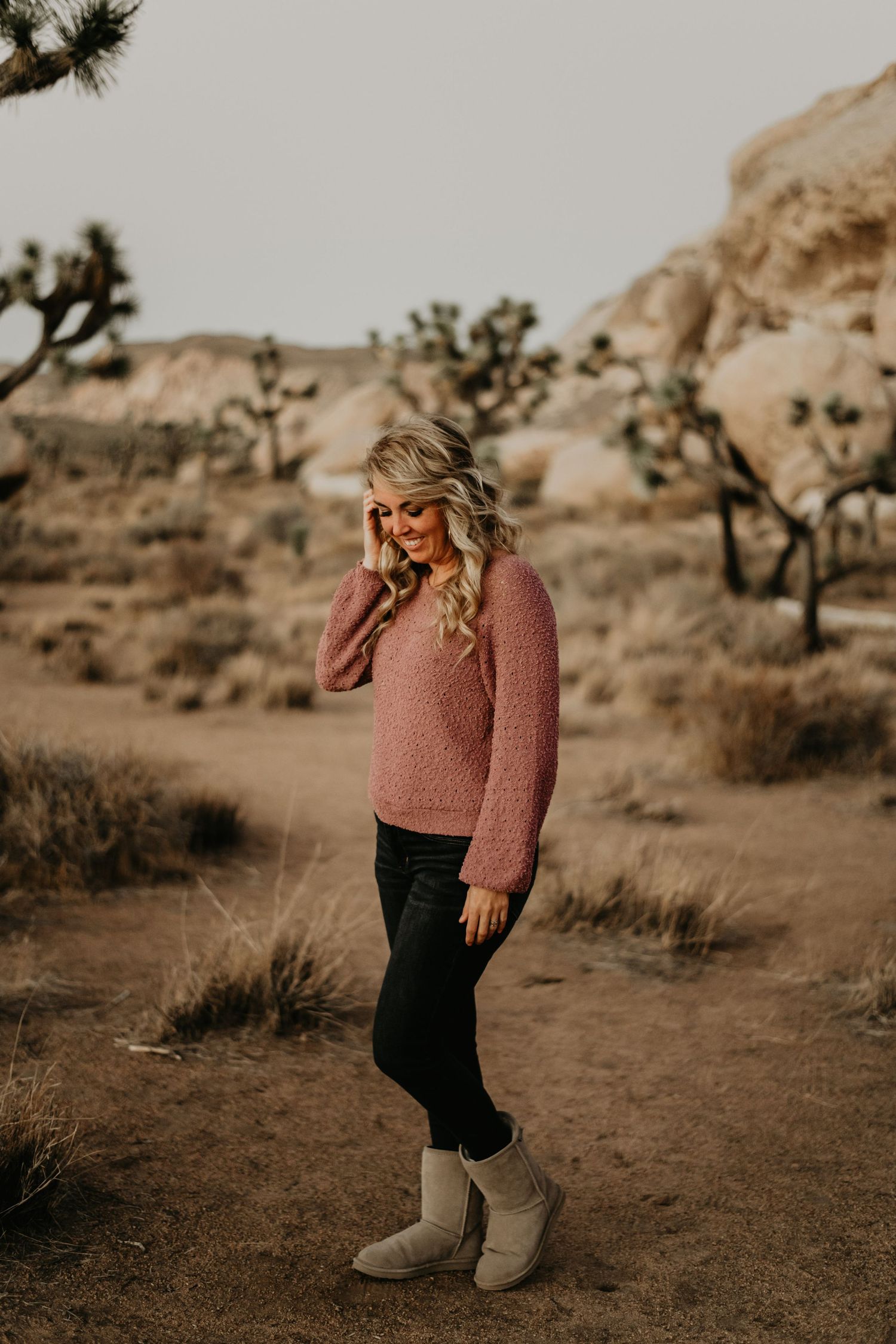 Desert portrait featuring cozy pink sweater against backdrop of Joshua trees.