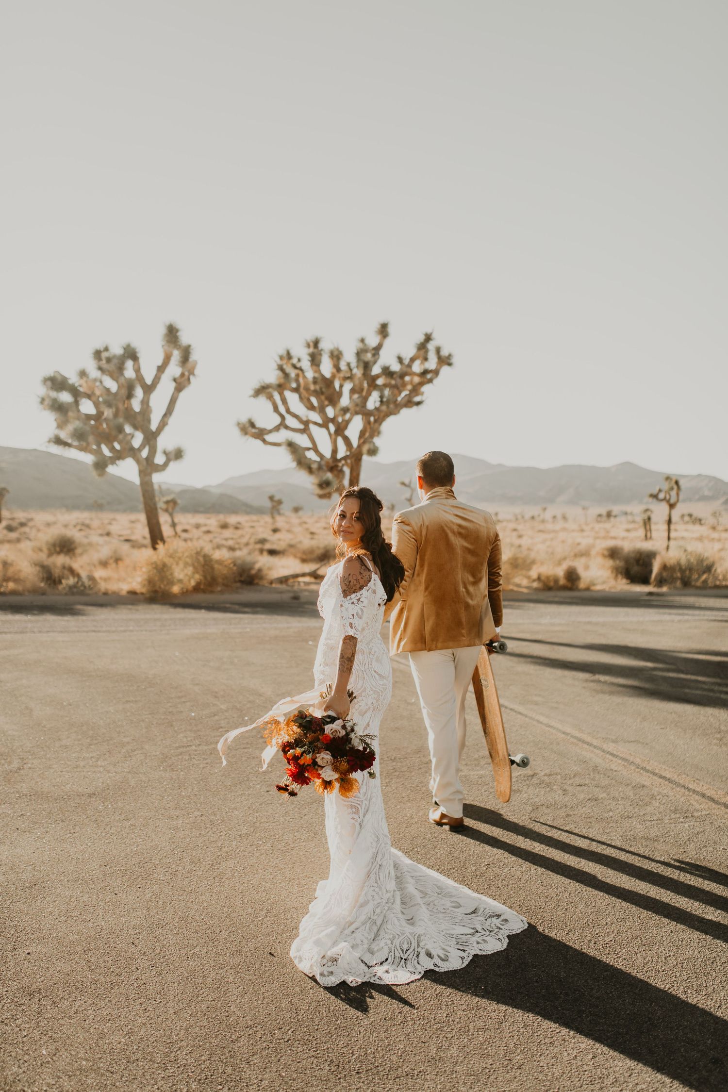 Desert wedding photography in Joshua Tree with couple walking on empty road in California.