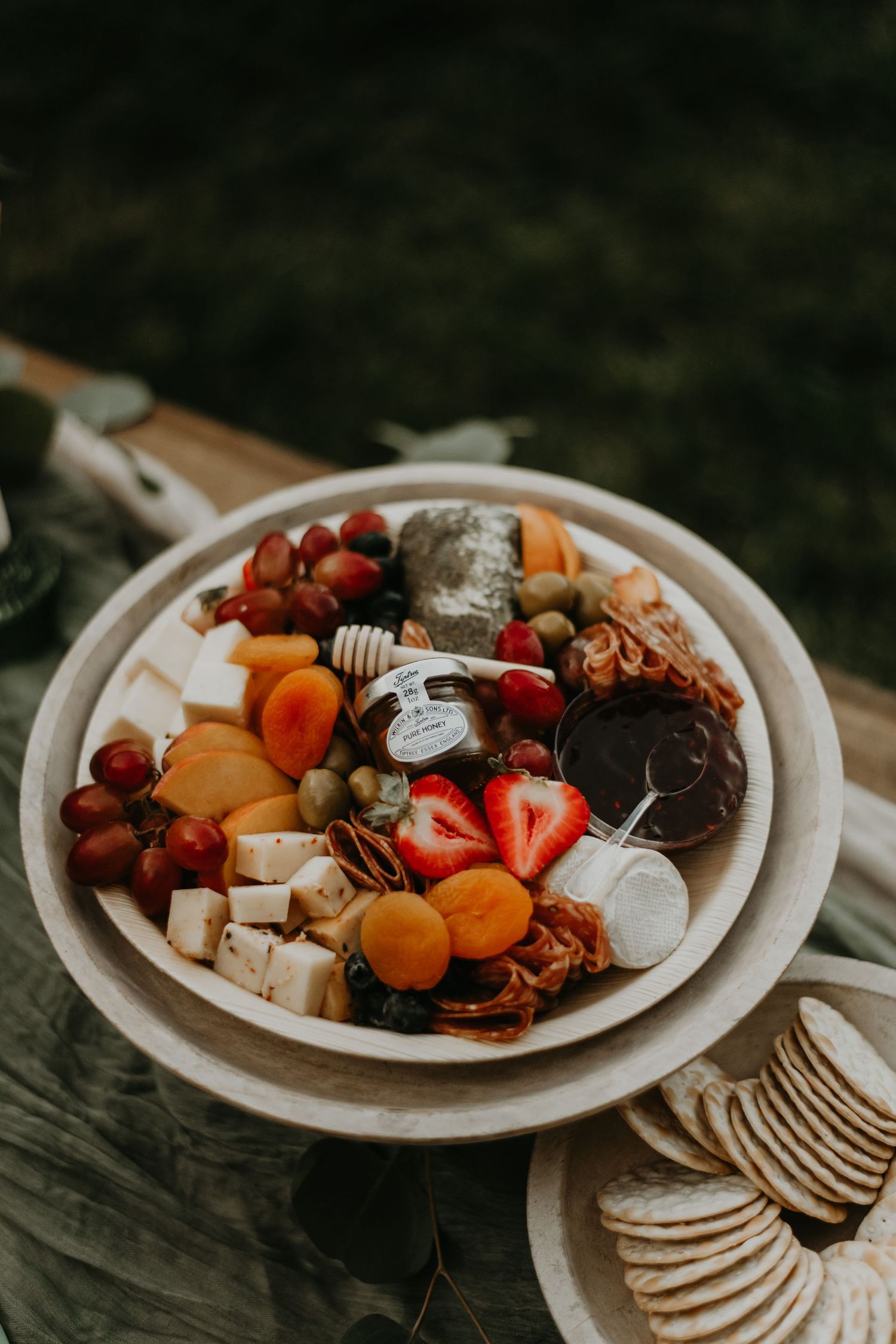 Rustic charcuterie board with fresh fruits, crackers, and assorted snacks.