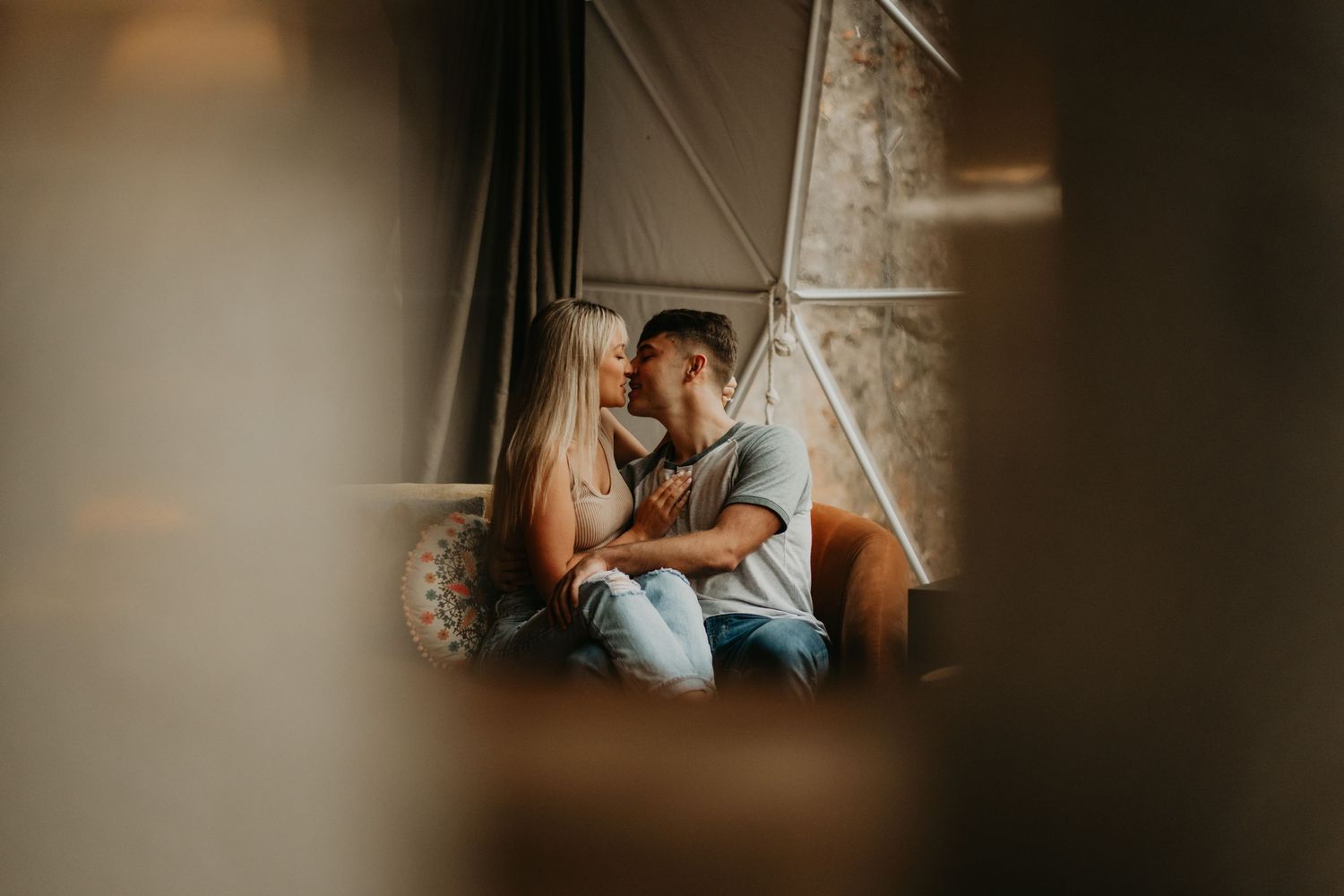 An intimate couple sharing a tender moment by a window in soft lighting.