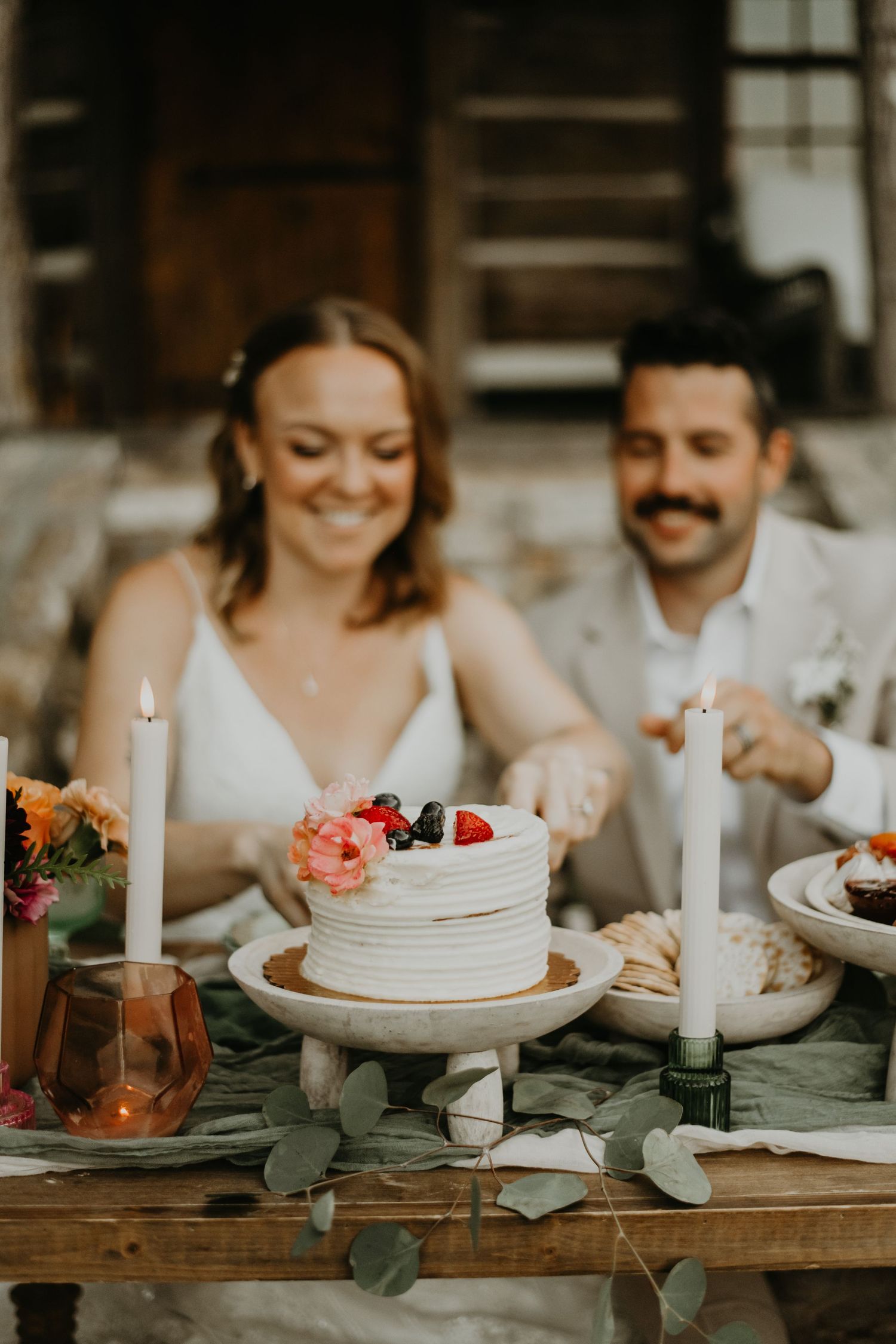 Elegant wedding table setting with white cake, candles, and eucalyptus leaves in north Carolina.