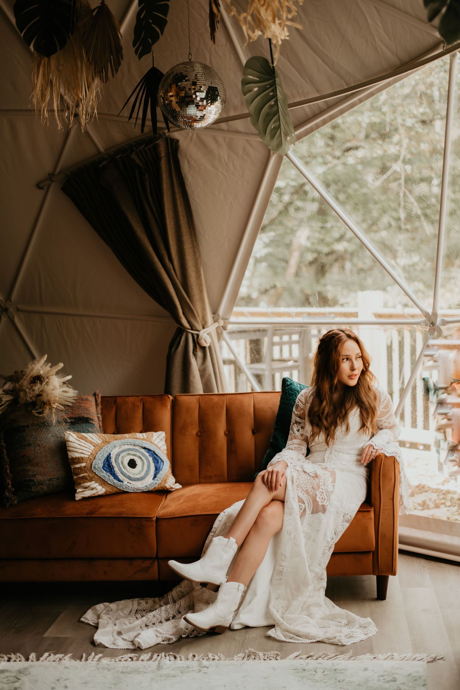 Boho wedding seating area with caramel leather couch and decorative pillows in outdoor tent.