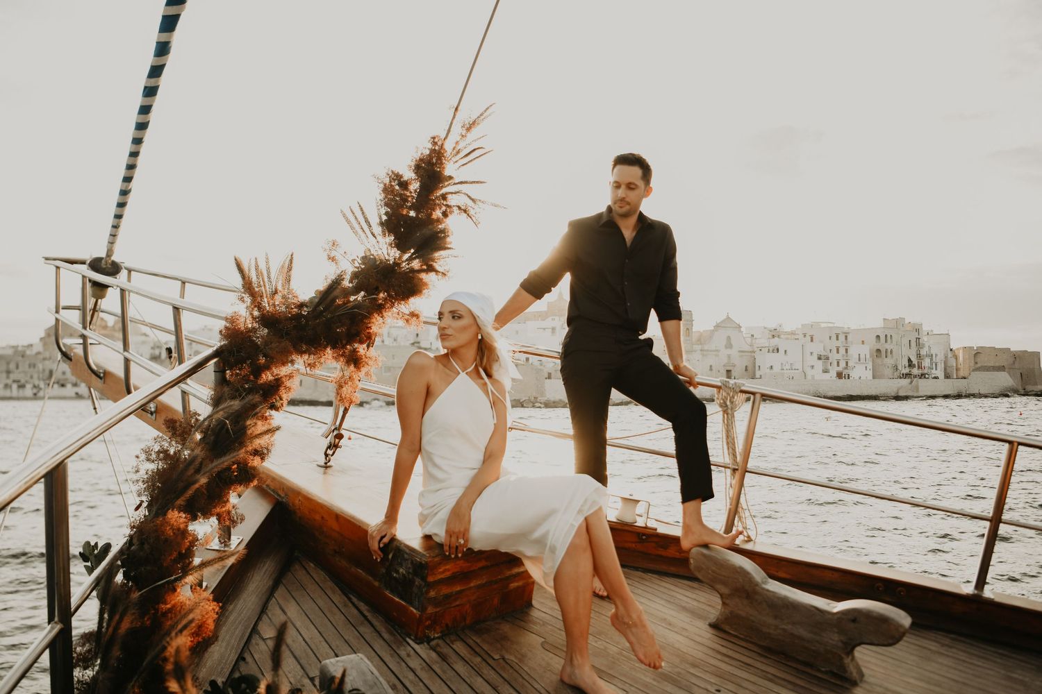 A wedding photoshoot on a decorated boat deck with floral arrangements and coastal views.