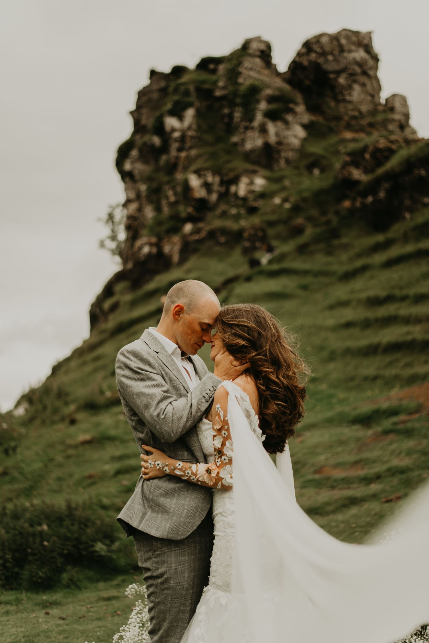 Intimate wedding portrait of a couple embracing against dramatic cliffs in Scotland's rugged landscape in Isle of Skye Scotland.