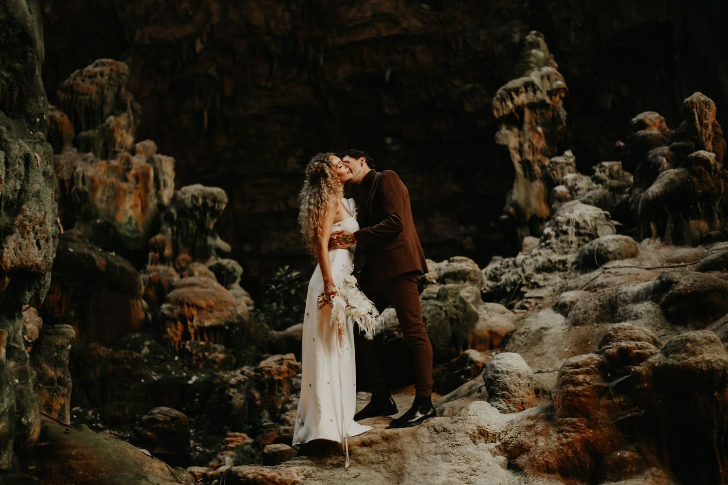 Romantic couple standing among rocky cliffs in dramatic landscape.