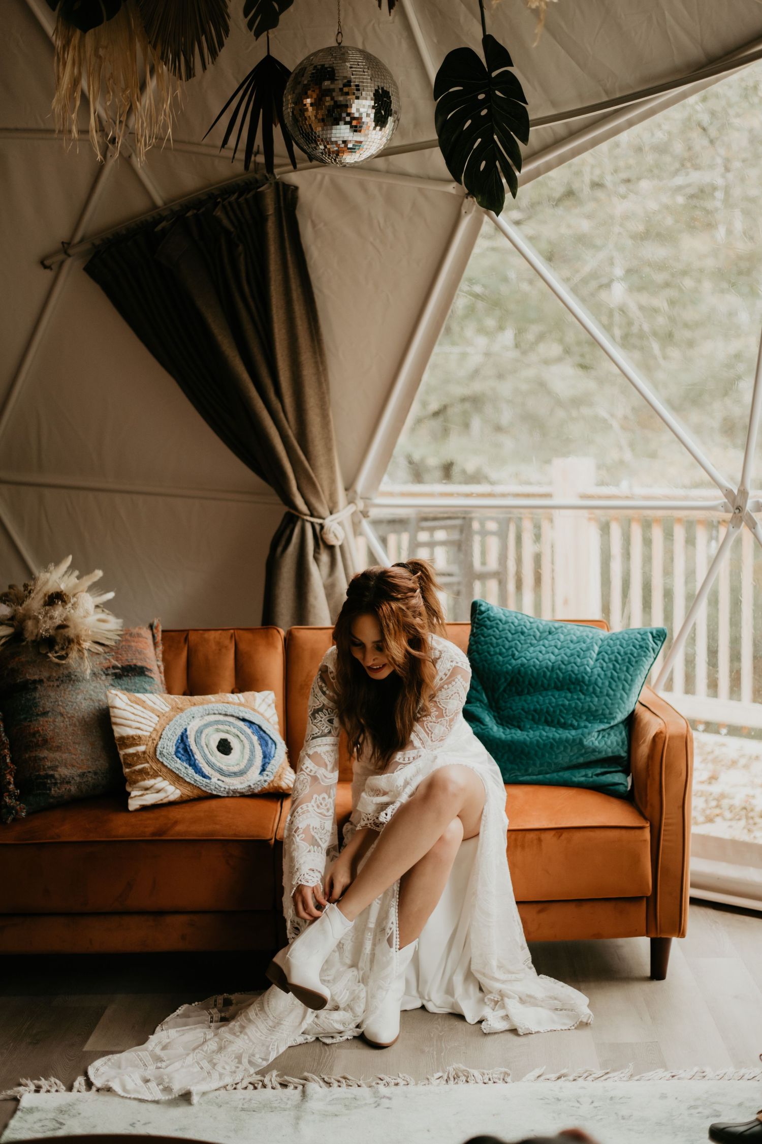 Cozy lounge area with orange velvet couch and teal accent pillows in tent reception space.