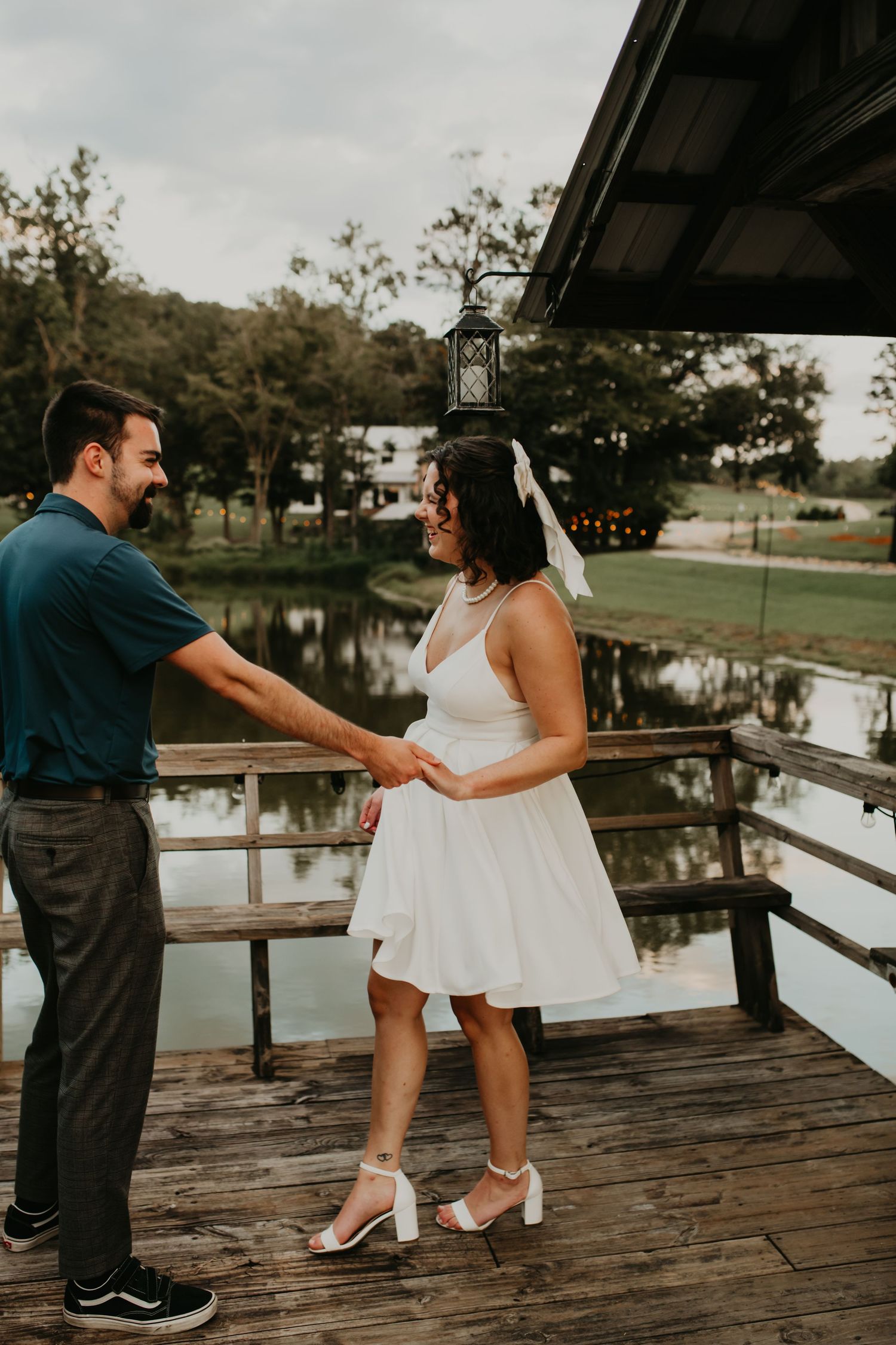 Couple dancing together on wooden deck overlooking a pond during an overcast day.