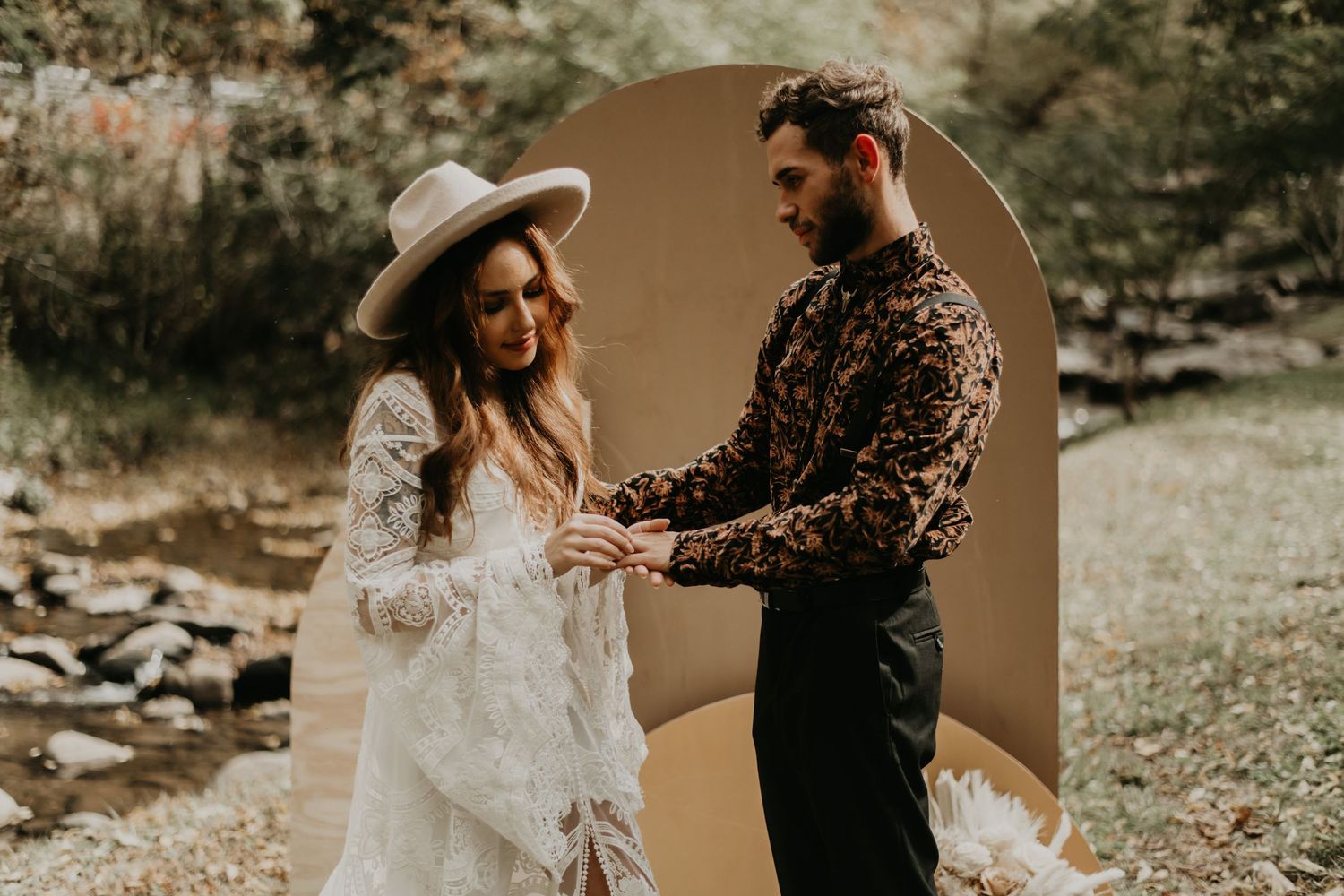 Desert-toned arch frames wedding couple in natural outdoor setting with rocks and greenery.