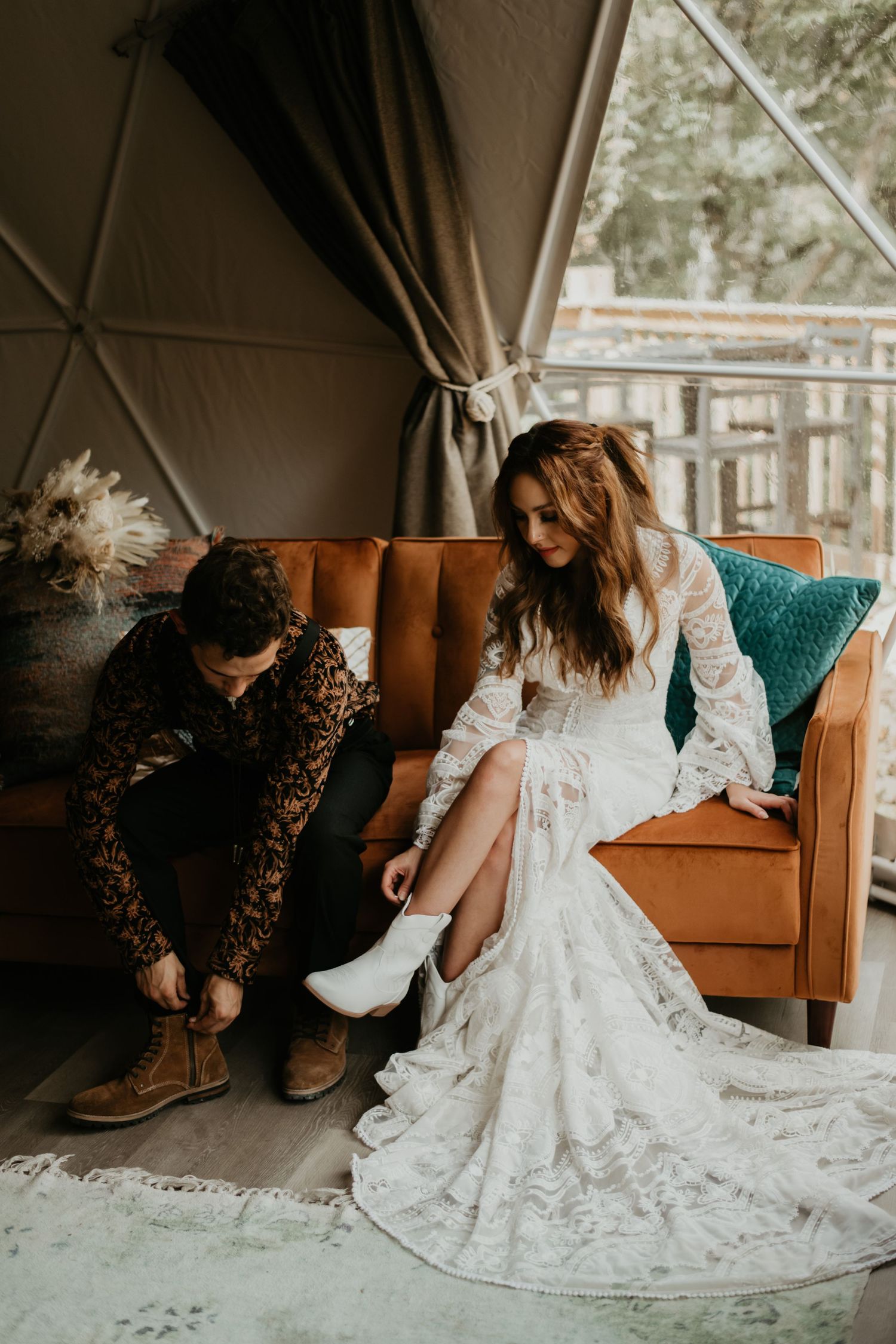 Couple getting ready in a glamping tent with tan leather couch and turquoise accent pillows.