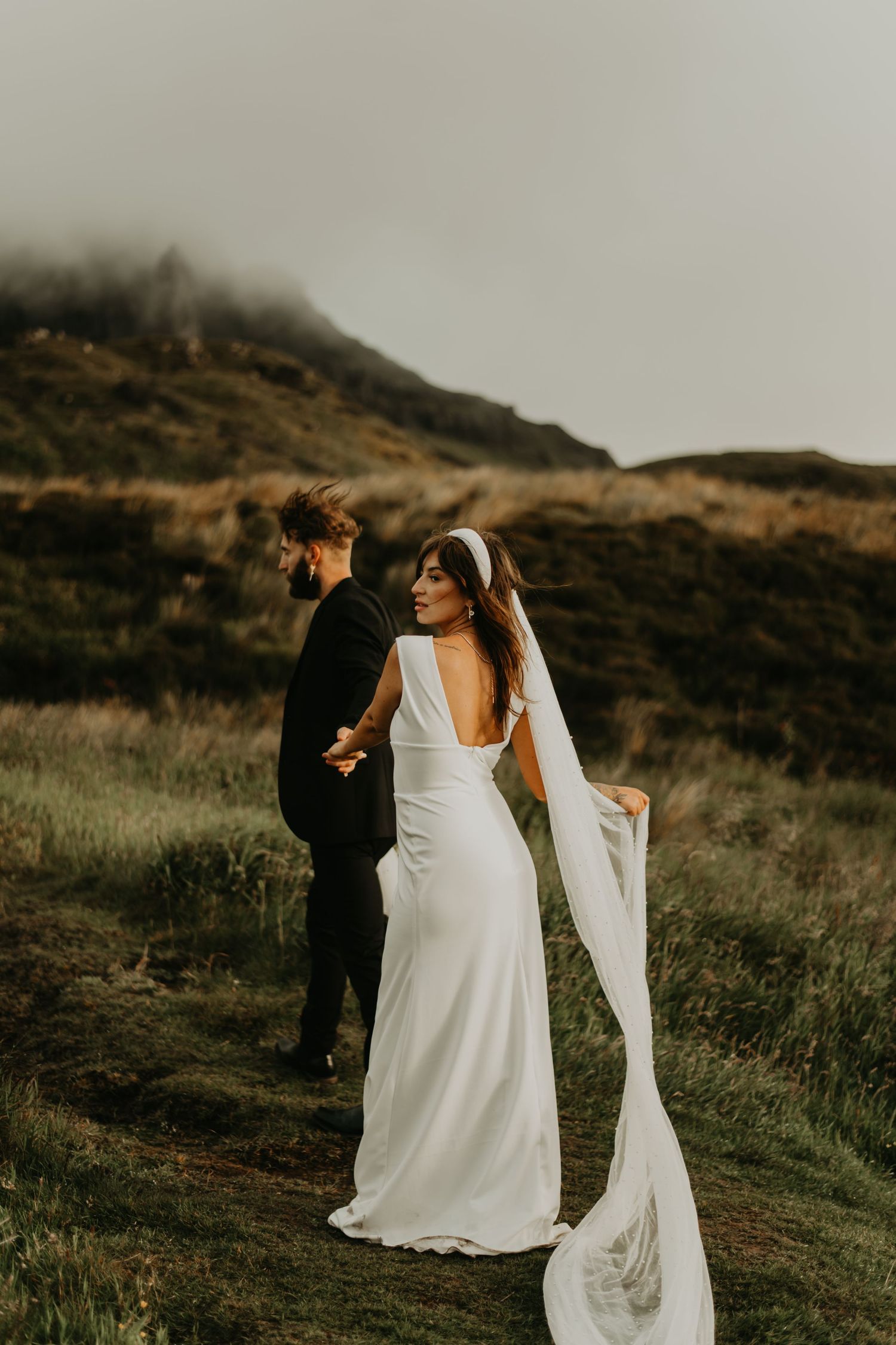 A couple in wedding attire embrace on a misty mountainside during their elopement in isle of Skye Scotland.
