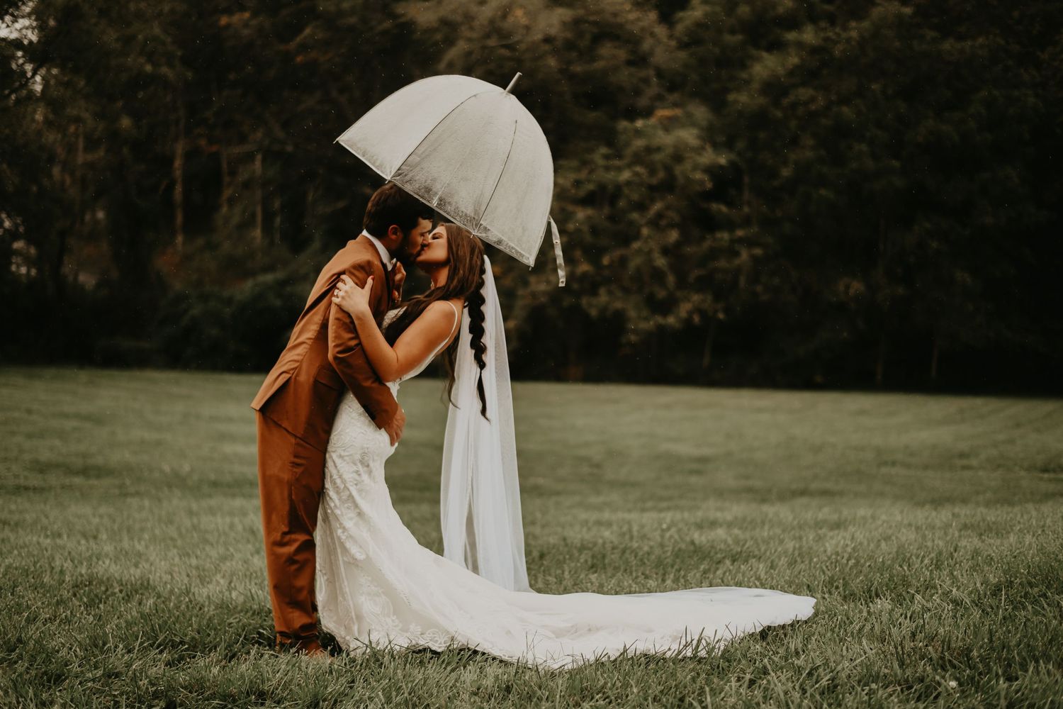 A romantic wedding moment under a white umbrella on a misty green field in north Carolina.