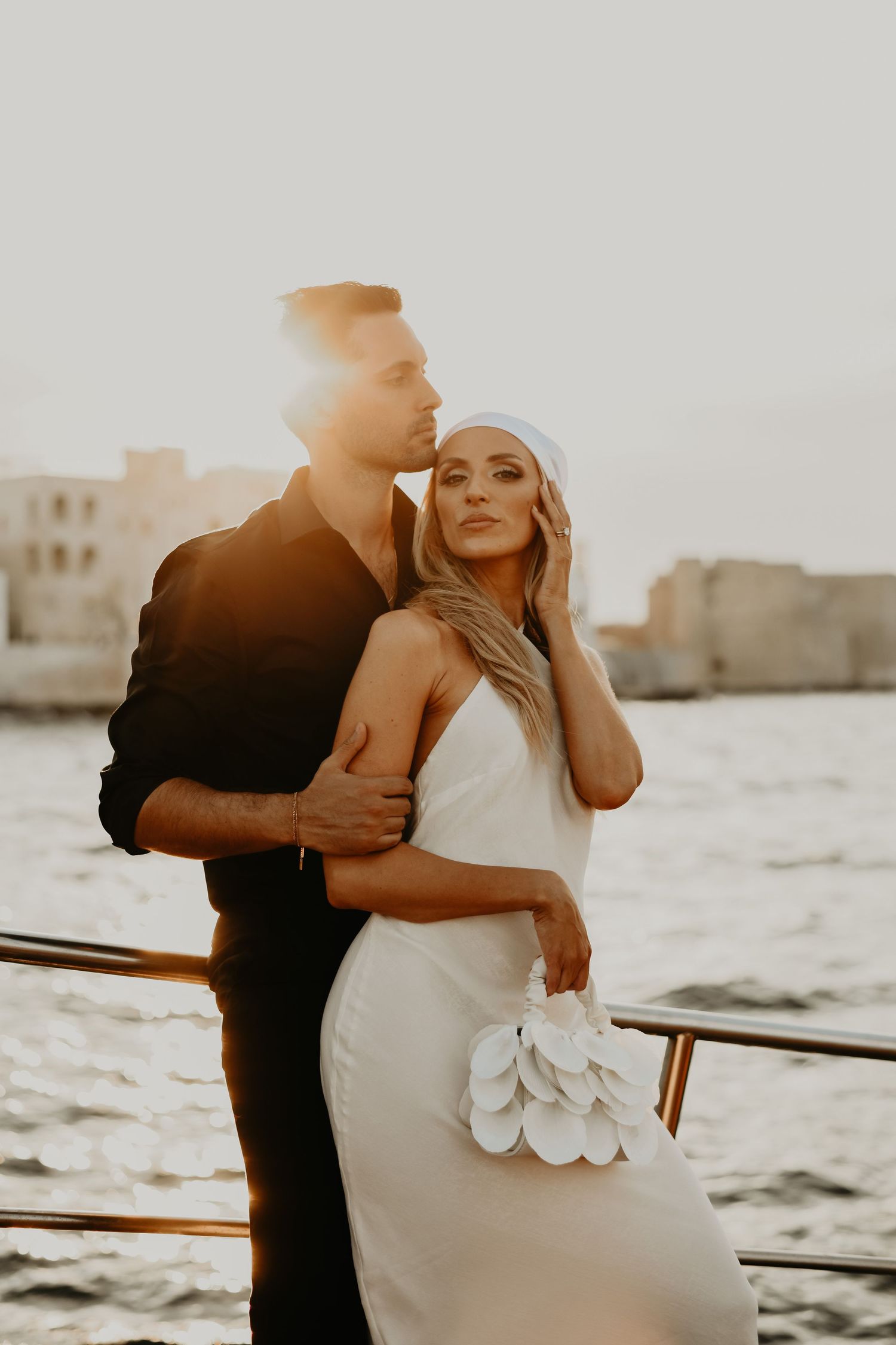 A romantic sunset portrait on a boat with golden light and coastal buildings in background in Italy.