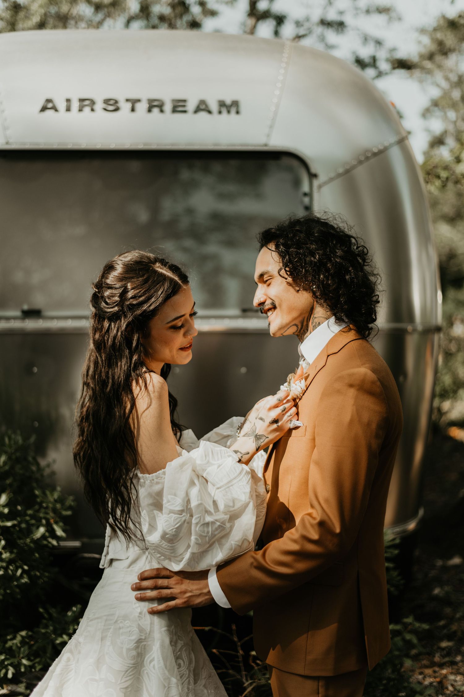 Happy couple in formal attire sharing intimate moment in front of vintage Airstream in Cape Cod.