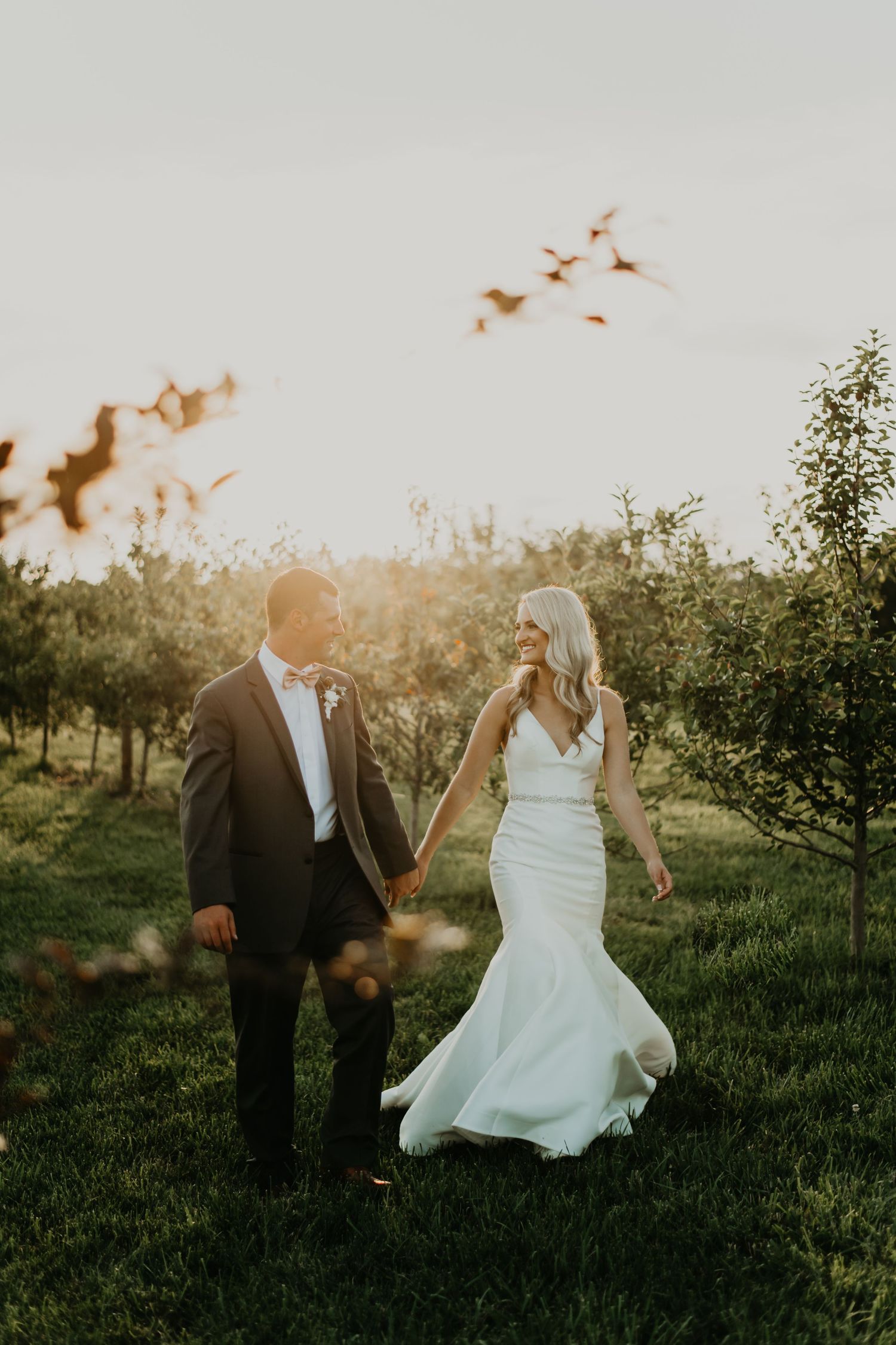 Newlyweds dancing in field at sunset with bride's dress flowing in golden light in north Carolina.