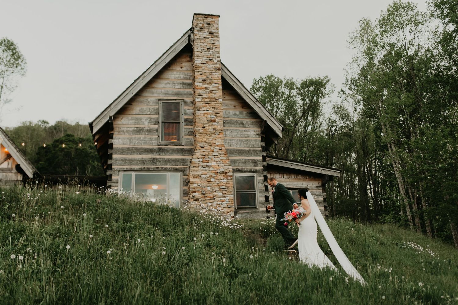 Rustic stone cabin provides romantic backdrop for wedding photos in tall grass meadow in Asheville, North Carolina.