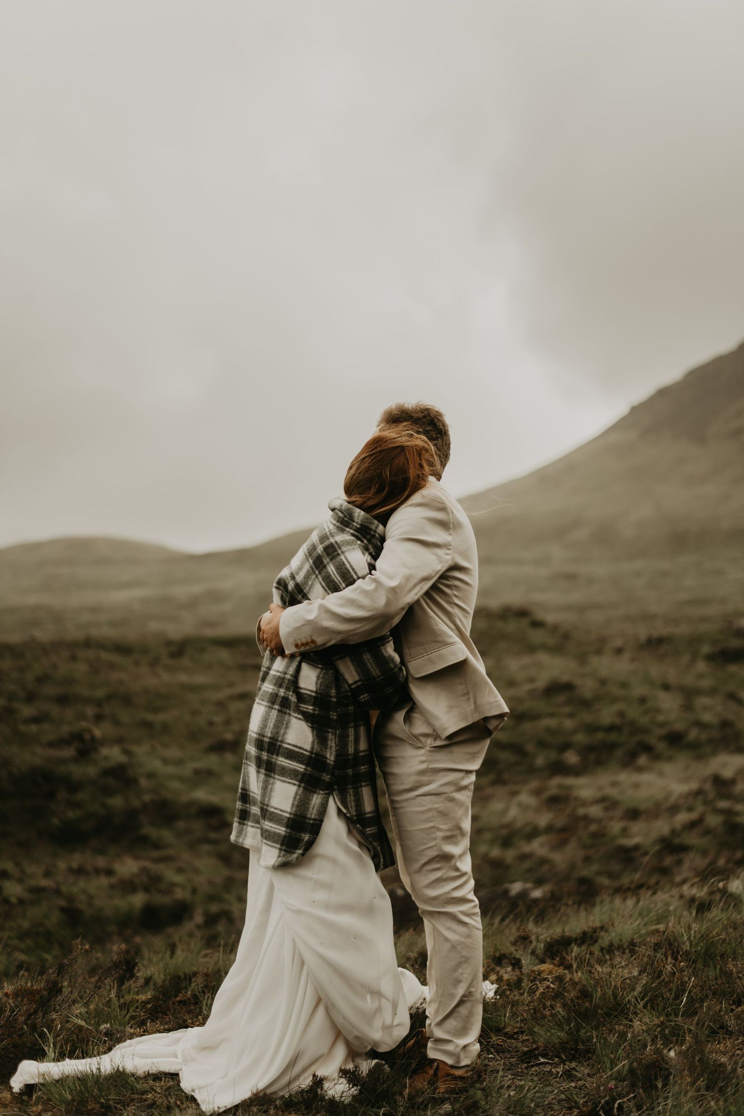 Couple shares intimate moment during wedding photos on misty mountainside in Isle of Skye Scotland.