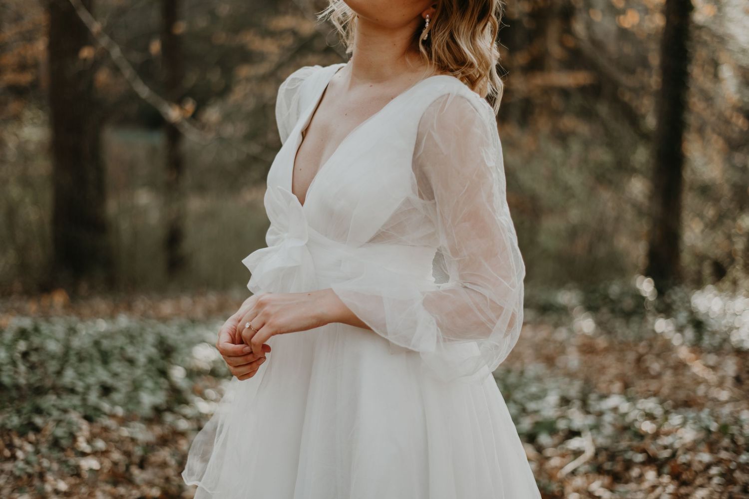 Elegant bridal gown with sheer puff sleeves amid autumn forest setting in north Carolina.