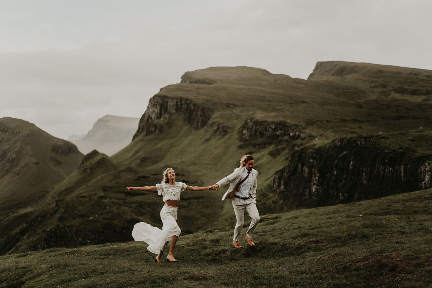 A couple dances joyfully on a scenic cliffside in Scotland's rugged landscape in isle of skye Scotland.