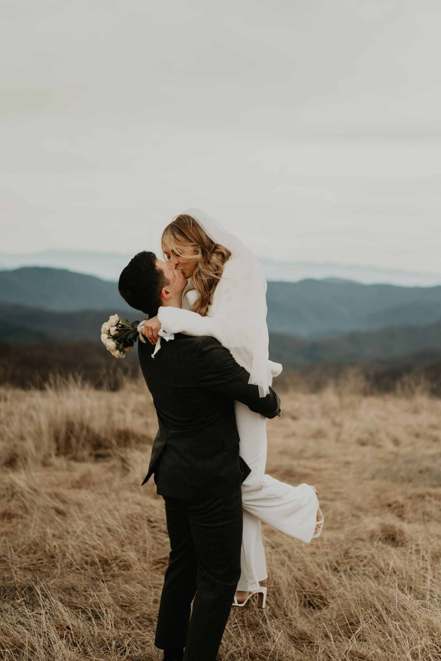 A romantic lift during a wedding photo session with mountains in the distance in North Carolina.