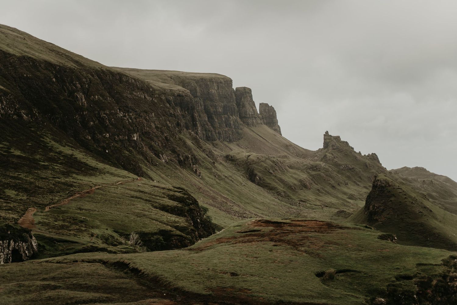 Misty mountain landscape with dramatic cliffs and rolling hills in moody weather in isle of Skye Scotland.