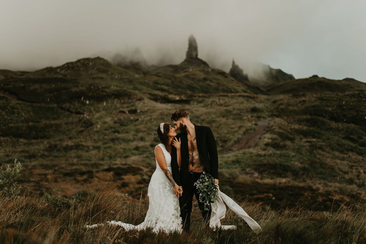 A dramatic wedding portrait on a misty Scottish mountain with dramatic rocky peaks in background in Isle of Skye Scotland.