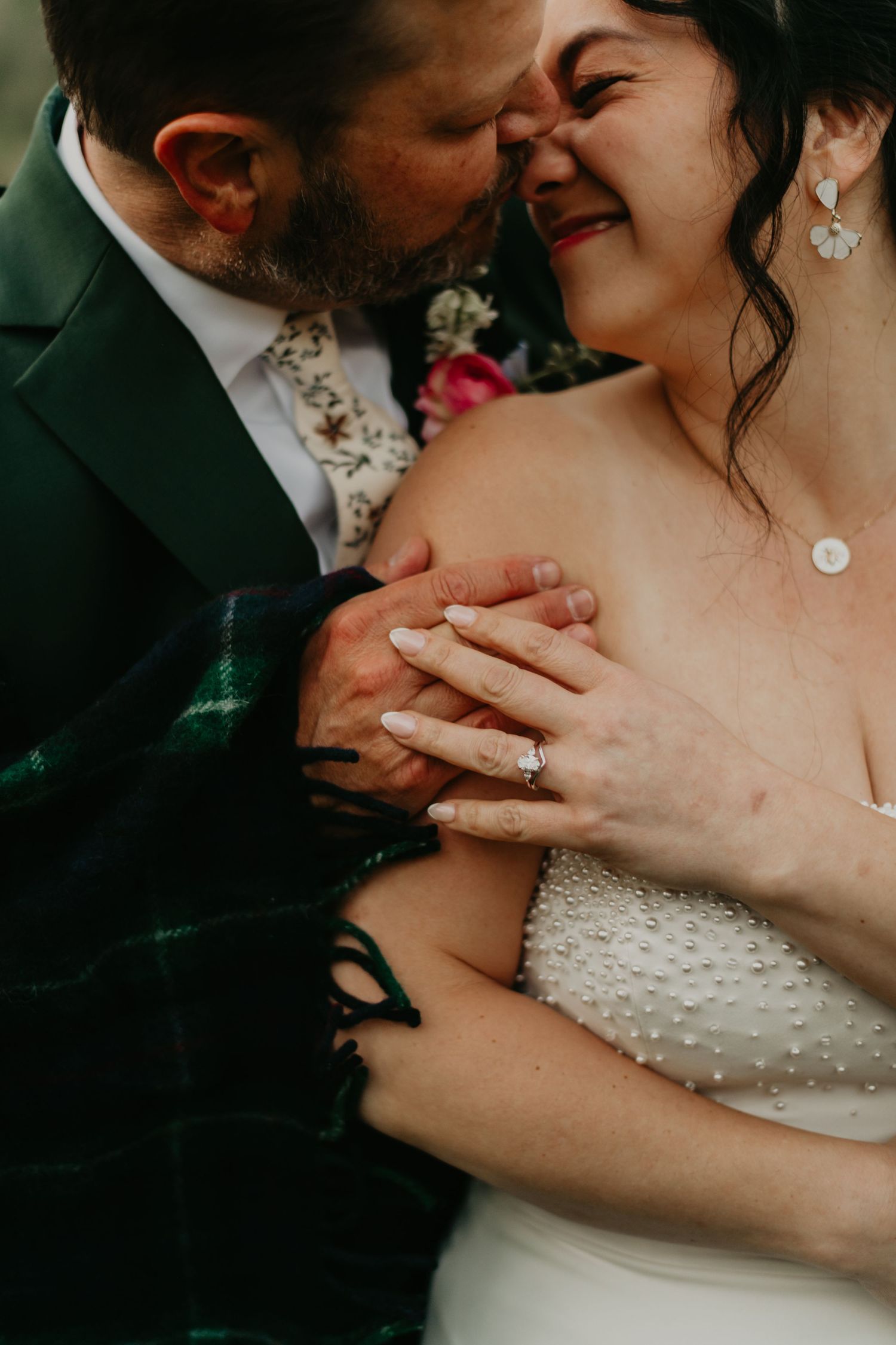 Close-up intimate wedding photo showing couple embracing, with bride in white beaded gown and groom in dark suit.