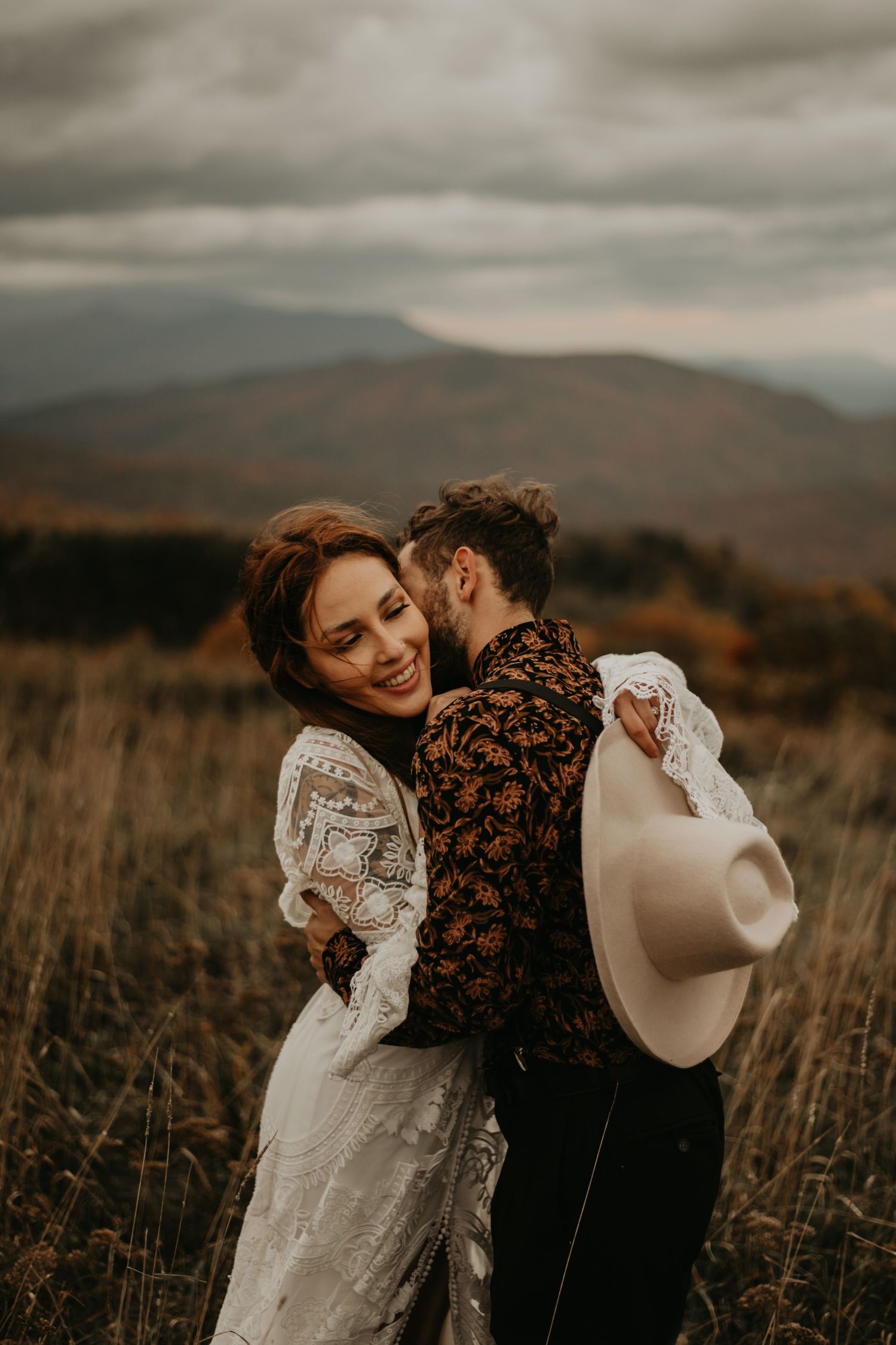 A tender moment between newlyweds against a backdrop of misty mountains and autumn colors in North Carolina.