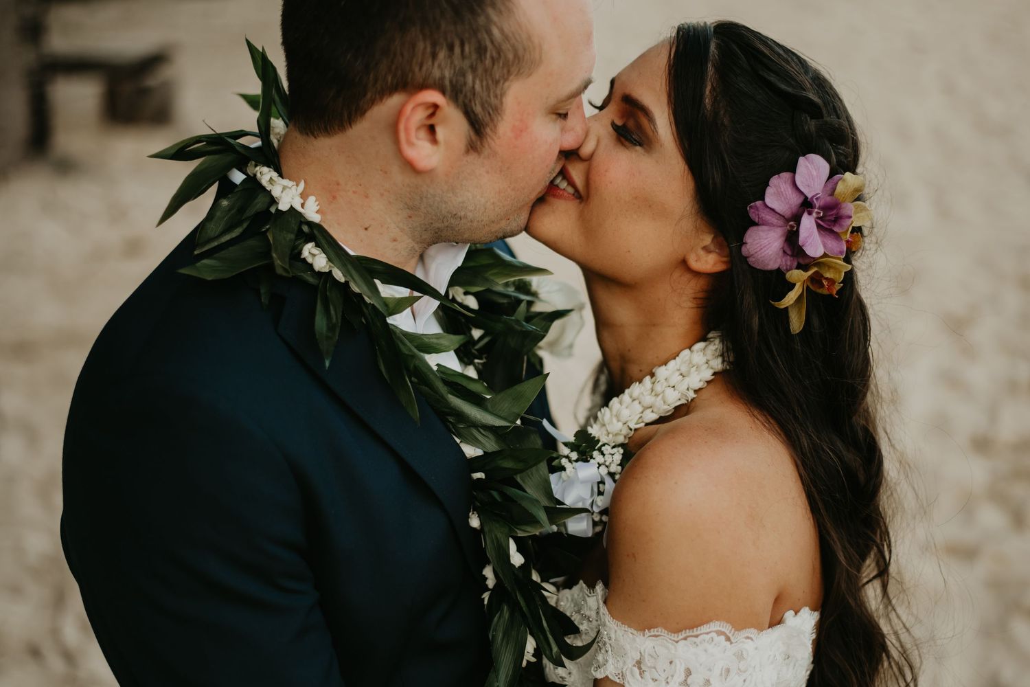 A tender wedding moment captured with traditional Hawaiian leis and tropical flowers in Hawaii.