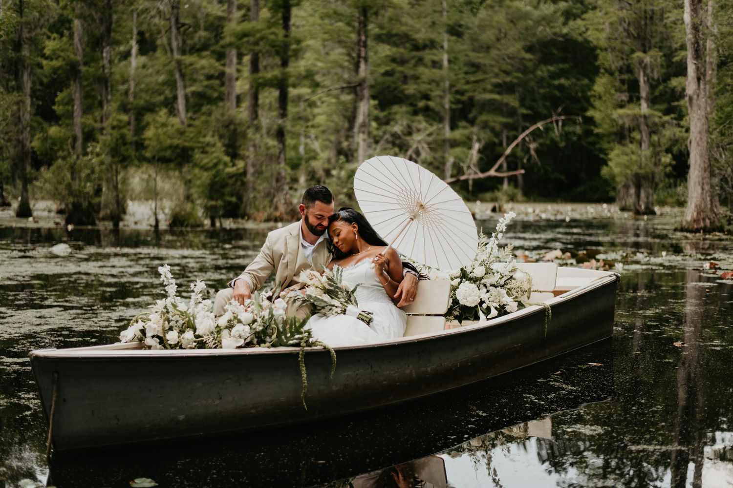 Romantic boat scene on a tranquil lake adorned with white flowers and parasol in Charleston South Carolina.