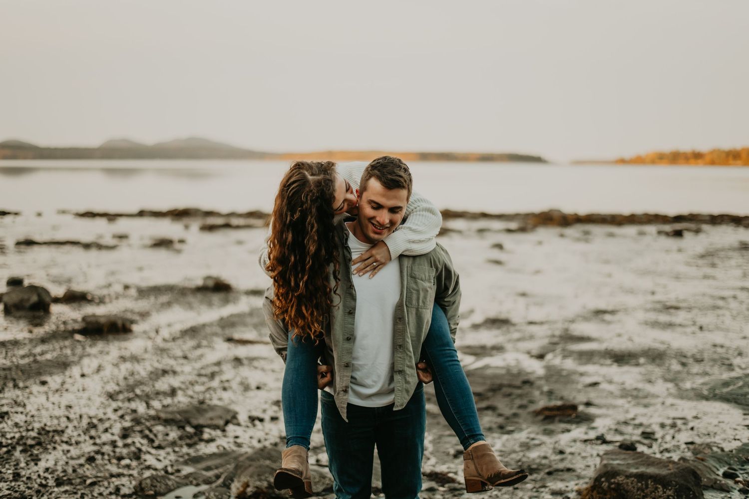 Two people walking together along a scenic coastline at sunset.