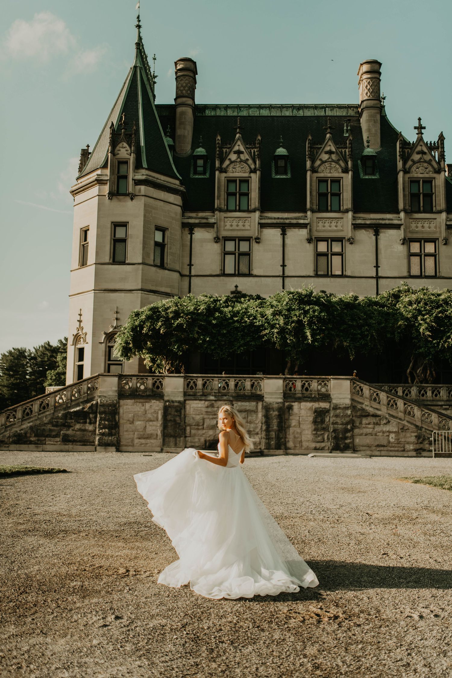 A flowing white wedding dress swirls in front of a grand historic castle building in Asheville north Carolina.