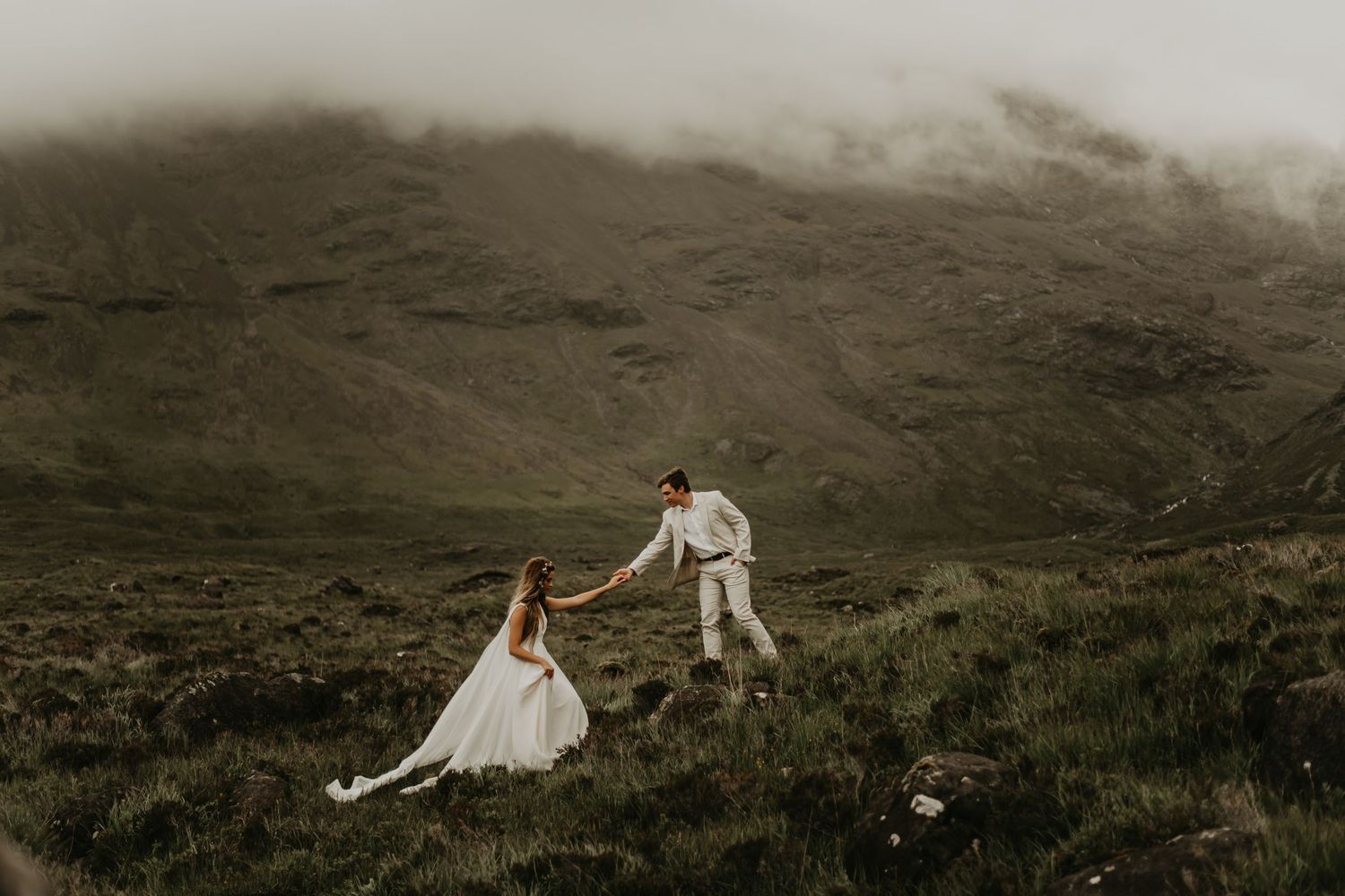 A scenic mountainous landscape with fog rolling over green hills in a moody, atmospheric setting.