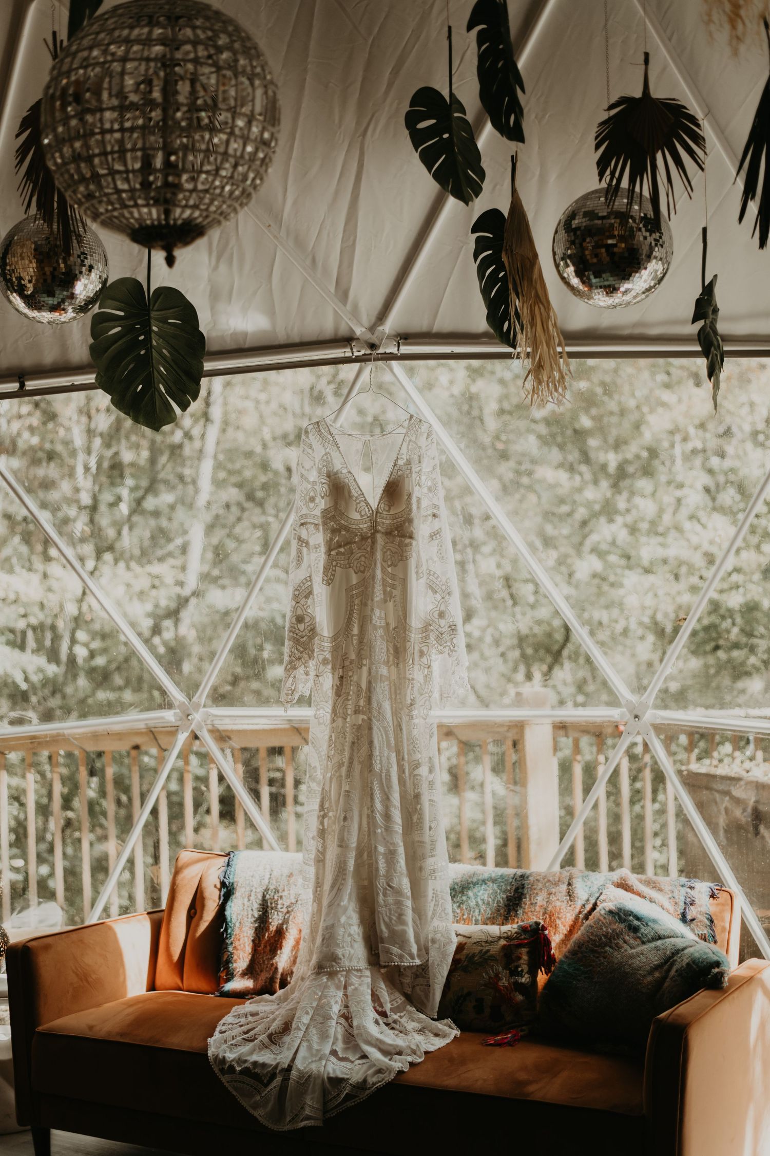 Bohemian wedding venue interior with macrame hangings and monstera leaves decorating the ceiling.