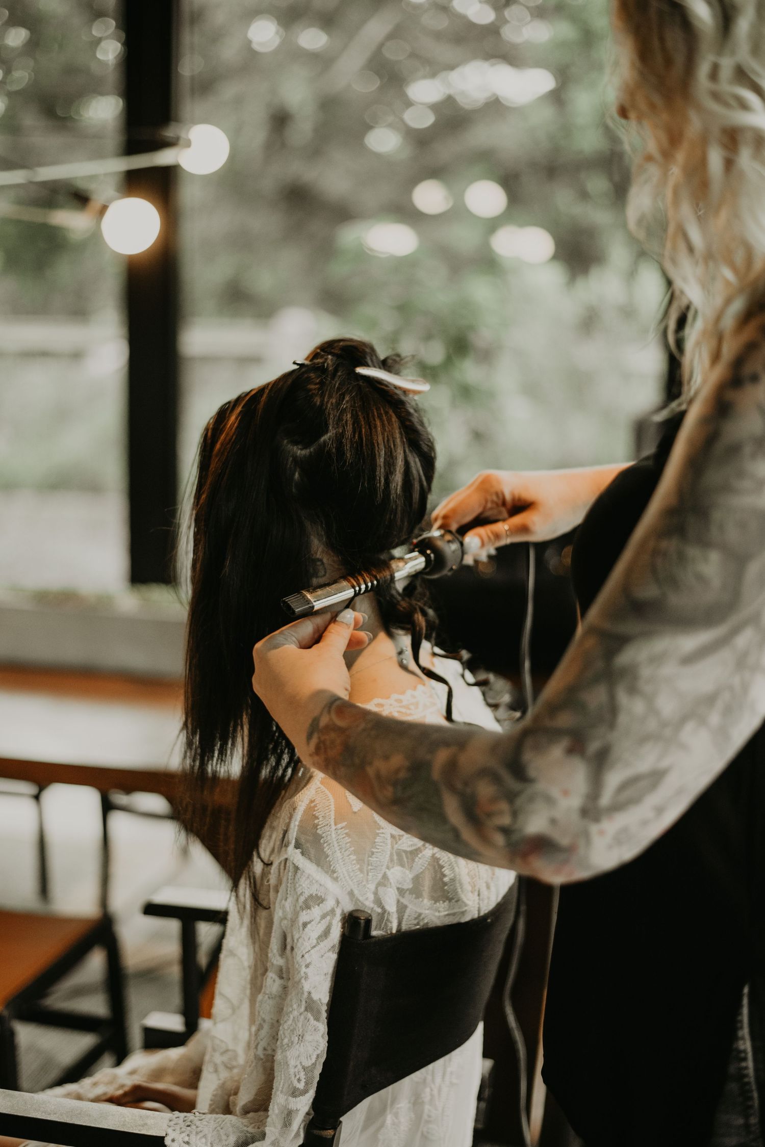 Wedding preparation scene showing hair styling in a softly lit room.