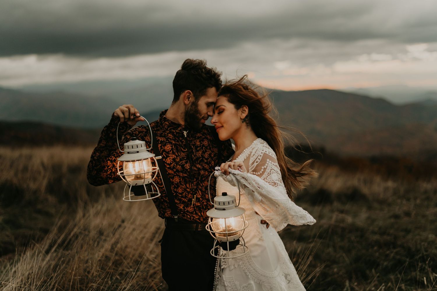 A couple holds lanterns in a moody field during golden hour in north Carolina.