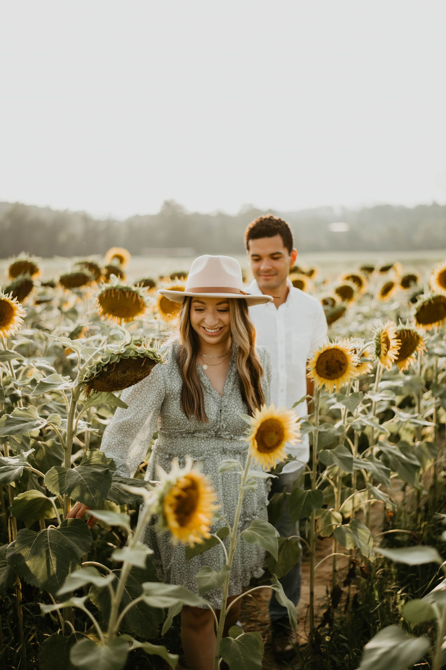 A couple embraces in a sunlit field of tall golden sunflowers during sunset creating a romantic summer atmosphere.