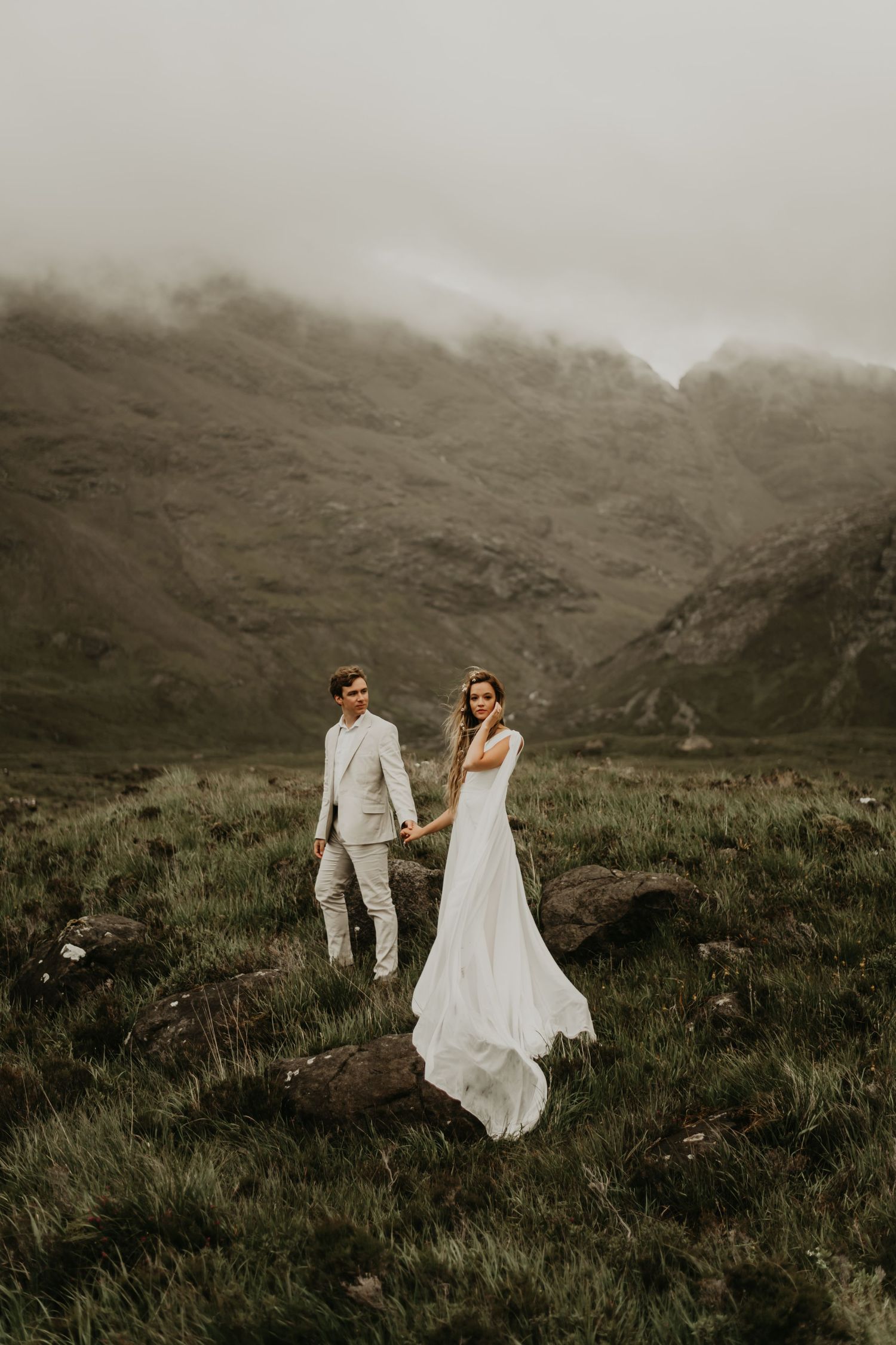 Ethereal wedding portraits showcase flowing dress against misty mountain backdrop in Isle of Skye Scotland.