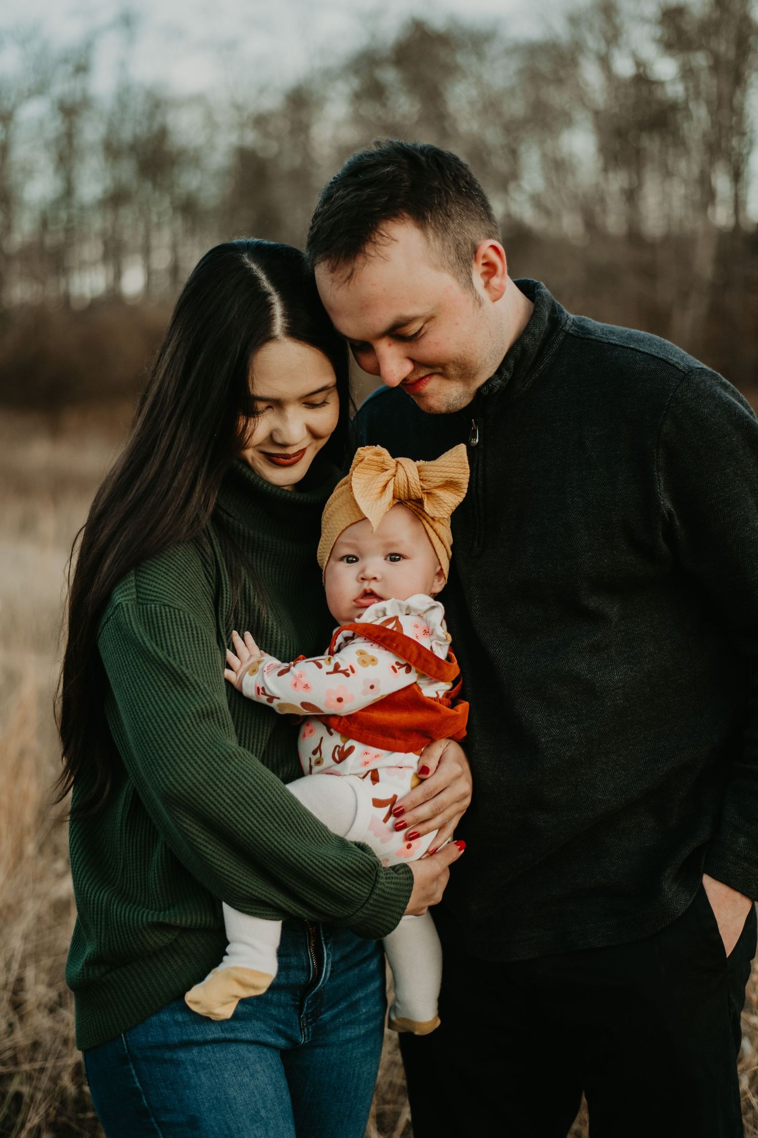 A family shares tender moments together during an outdoor autumn photoshoot in muted earth tones.