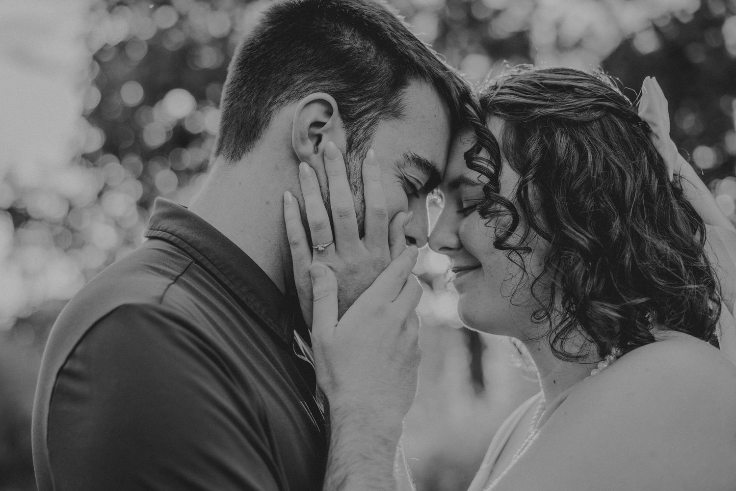 Black and white intimate portrait of a romantic couple sharing a tender moment in soft bokeh lighting.