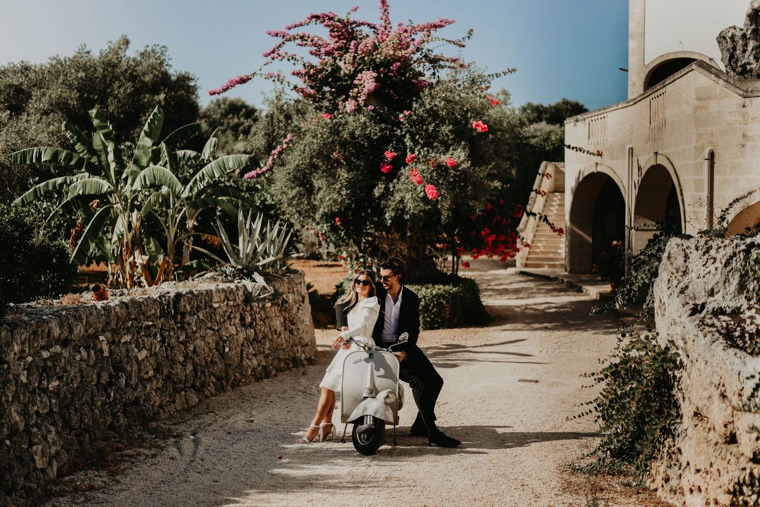 Wedding scene at Mediterranean villa with blooming bougainvillea and stone walls in Italy.