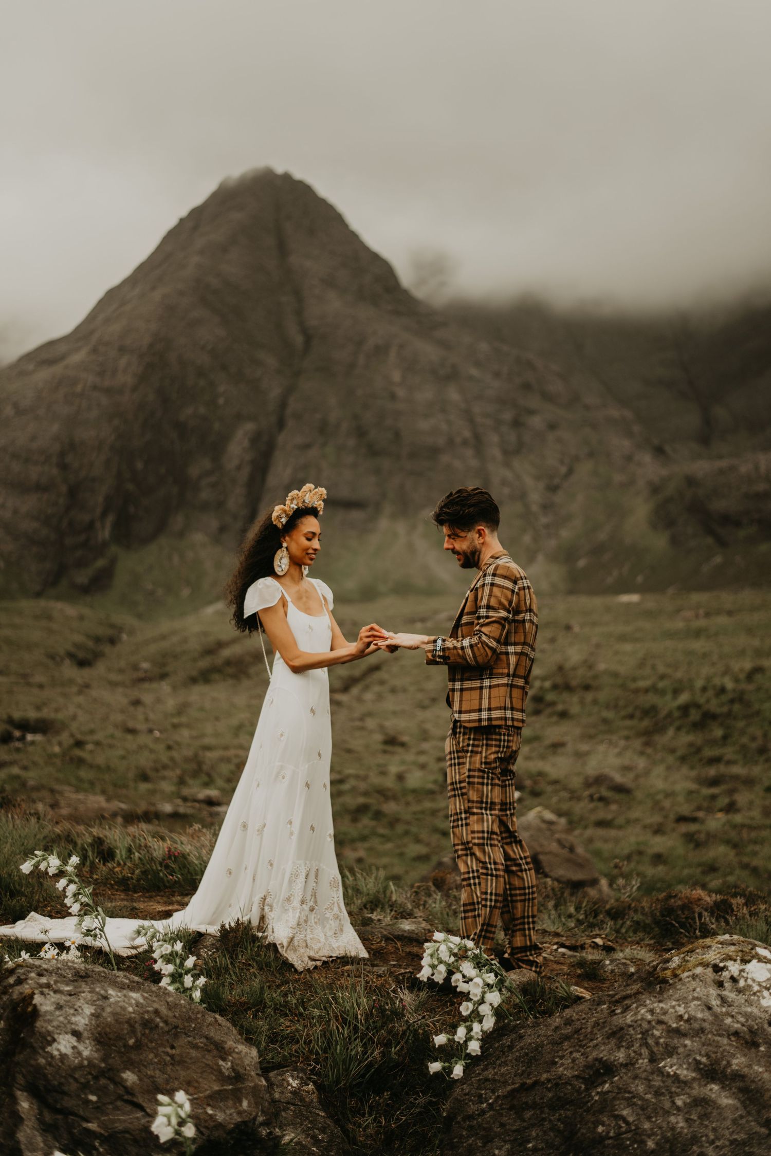 A couple exchanging rings during their mountain elopement ceremony with dramatic peaks behind them in isle of Skye Scotland.