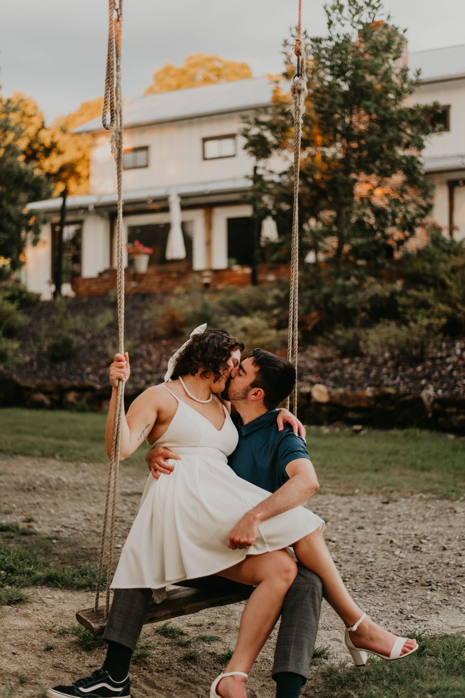 A romantic couple sharing tender moments on a swing set during golden hour sunset.
