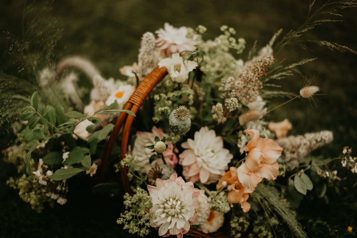 Delicate floral arrangement with peach and white blooms set against a dark background.