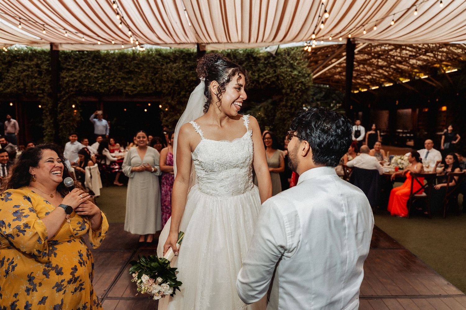Newlyweds share their first dance under decorative string lights at their reception.