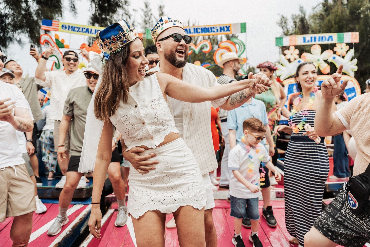 Festival crowd dances and celebrates together outdoors on a sunny day at a summer event.