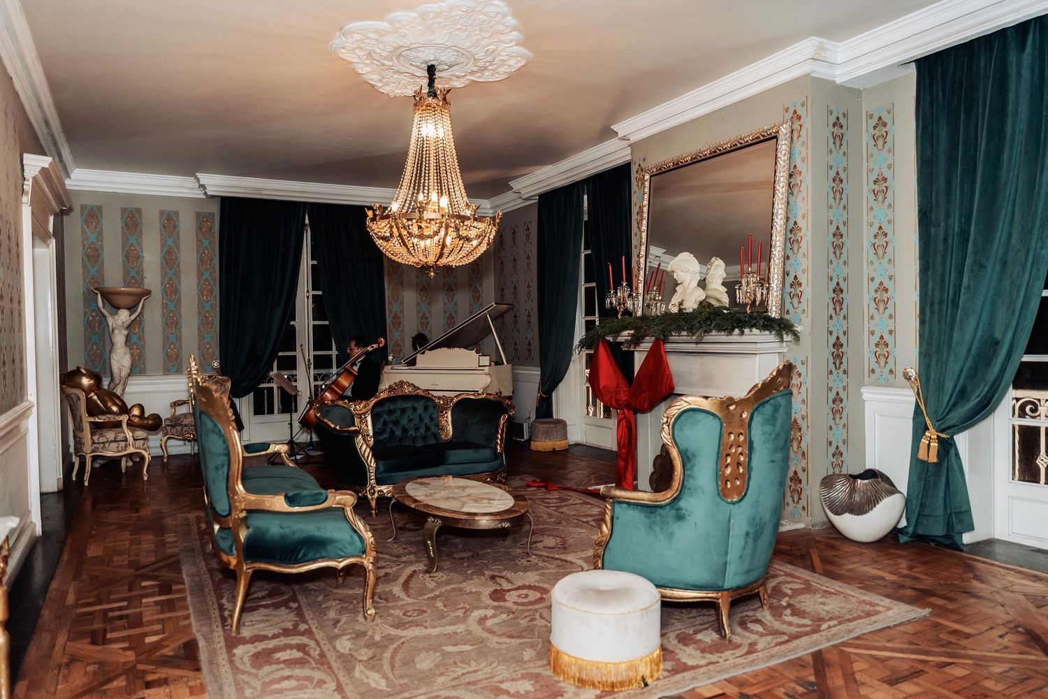 An elegant room with vintage furniture, teal curtains, and a crystal chandelier.