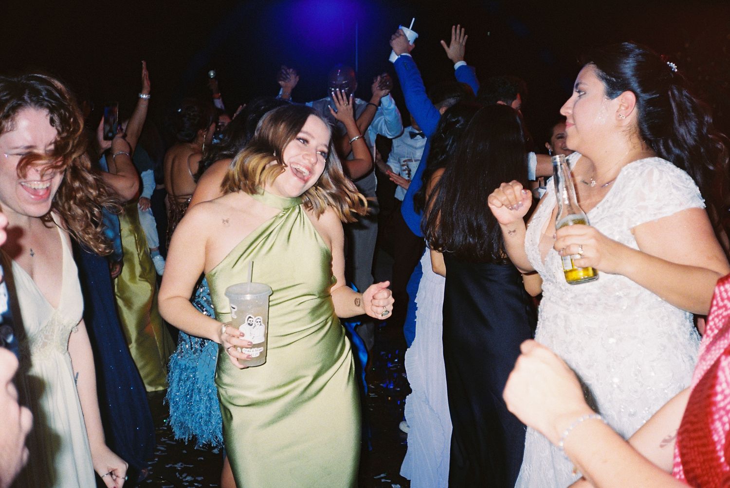 People dancing and celebrating at a party with blue lighting and festive atmosphere.